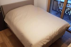 弗利姆斯2.5 Room Apartment in Center of Flims. Ski in/out的带阳台的客房内的一张白色床