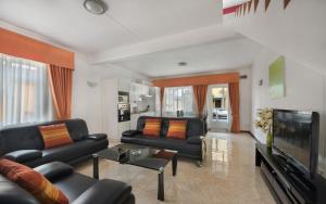 康隆尼角瓦纳一室公寓酒店的客厅配有黑色沙发和平面电视。