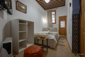 舍夫沙万Riad Bin Souaki的一间卧室配有一张床和一张桌子及凳子