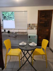博尼图Bonito HI Hostel e Pousada的厨房里配有一张桌子和两把黄色的椅子