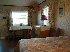 卡文迪西埃文利亚小屋酒店的一间卧室配有一张床、一张桌子和一个窗户。