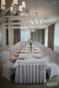 ŻyrakówHotel Millenium的一张长桌子,房间配有白色椅子