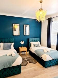 伦敦Private House With FREE Parking的一间蓝色卧室,配有两张床和吊灯