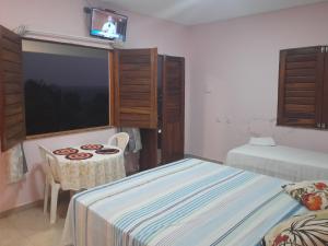 伊卡普伊Pousada Chalés do Castelo的一间卧室配有两张床、一张桌子和一台电视。