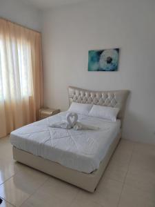 瓜埠Cozy 3 Bedrooms Apartment Langkawi的卧室配有白色的床,上面有弓