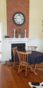 布罗肯希尔古姆围场乡间小屋农家乐的一间用餐室,配有桌子和壁炉上方的时钟