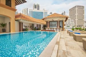 新加坡Orchard Rendezvous Hotel by Far East Hospitality的一个带椅子的游泳池,后方是建筑