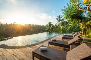德格拉朗GK Bali Resort的度假村的游泳池,配有椅子和阳光