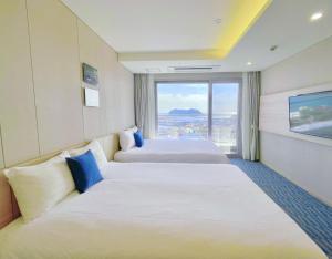 西归浦市Hotel bridge Seogwipo的酒店客房设有两张床和大窗户。