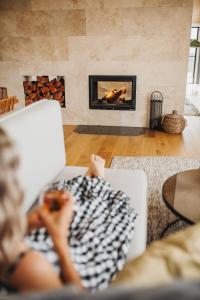 Stokes BayStowAway Kangaroo Island的坐在客厅沙发上的女人,客厅里设有壁炉