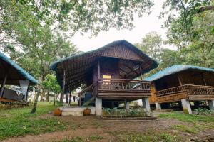 CavintiAlmost Heaven Lake Resort by Cocotel的森林中茅草屋顶的房子