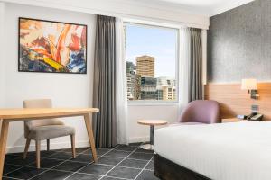 悉尼Furama Darling Harbour的配有一张床、一张书桌和一扇窗户的酒店客房