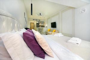 阿拉木图уютная квартира-студия в центре Алматы的白色的床,带紫色和白色枕头