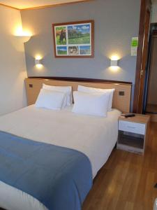 欧里亚克Hôtel Restaurant Campanile Aurillac的卧室配有一张带两个枕头的大白色床