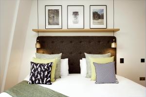 伦敦Wilde Aparthotels London Covent Garden的一间卧室配有一张带枕头的床,墙上挂有图片