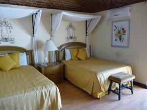 瓜纳华托卡斯提罗桑塔赛斯利亚酒店的一间卧室配有两张床、一张桌子和一盏灯。