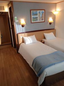 欧里亚克Hôtel Restaurant Campanile Aurillac的酒店客房设有两张床和两盏灯。