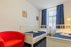 捷克布杰约维采Hotel Amadeus的一间卧室配有两张床和红色椅子