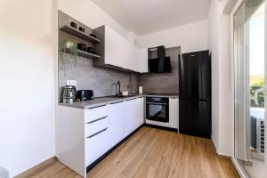 希贝尼克Apartman Ivana的厨房配有白色橱柜和黑色冰箱。