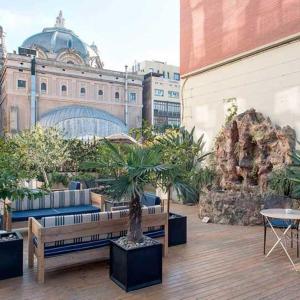 巴塞罗那兰布拉普拉提克酒店的一个带长椅和盆栽的庭院和一座建筑