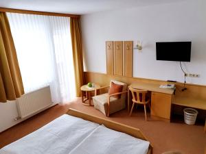 KaltenbergHotel Gästehaus Neubauer的酒店客房配有一张床、一张书桌和一台电视。