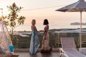 法拉萨纳Falasarna Luxury Villas的两名妇女站在一个眺望着大海的阳台