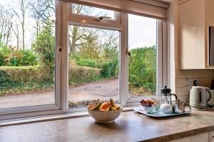 惠灵顿Finest Retreats - Glebe Cottage的窗户前有一碗水果的厨房台
