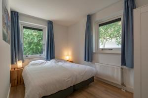 朱丽安娜多普Villa Duynopgangh 16 Julianadorp aan Zee的一间卧室设有一张床和两个窗户。