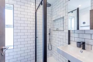 泰丁敦The Stanley Maisonette的白色瓷砖浴室设有水槽和淋浴
