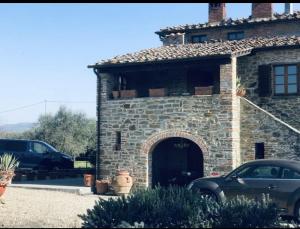 阿雷佐Casale di mamma Antonella的石头建筑,前面有停车位