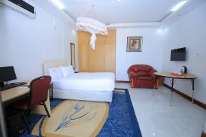 恩德培Frontiers Hotel & Conference Entebbe的酒店客房配有一张床、一张桌子和一把椅子。