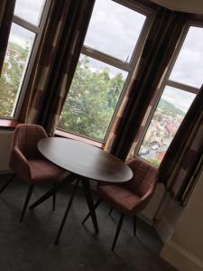 谢菲尔德Coniston Guest House的窗户间配有一张桌子和两把椅子