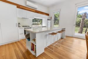 Lake TyersFlounder的厨房配有白色橱柜和带凳子的台面