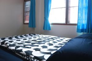 班敦孟ChillHouse24 @ DonMueang的卧室内的一张床铺,配有蓝色窗帘和窗户