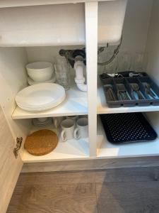 TotteridgeCosy North London 2 Bed Apartment in Woodside Park- Close to Station and Central London的装有盘子的橱柜和其他厨房用品