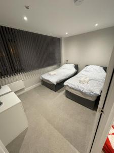 哈罗Whole apartment in Harrow Town centre的一间卧室设有两张床和窗户。