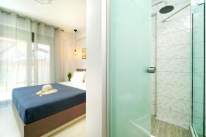 奥林匹亚达Theros By The Sea的一间卧室设有一张床和一个玻璃淋浴间