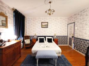 普莱利LA CHASSE ROYALE的一间卧室配有一张床、一张书桌和一个吊灯。
