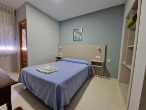 维尔根德尔卡米诺Hostal Soto的一间卧室配有蓝色的床和2条毛巾