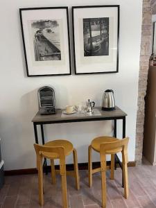 佩鲁贾Atelier Fuori Città的一张桌子、两把椅子和两张墙上的照片