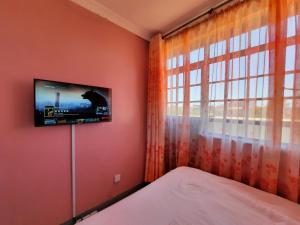 KikuyuPine Residency w Secure Parking, Wifi, Netflix & Rooftop Views的卧室设有窗户旁的墙壁上的电视