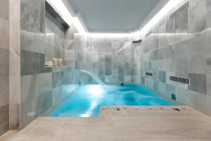格拉纳达Seda Club Hotel - Small Luxury Hotels的游泳池,浴室内,设有蓝色浴缸