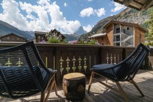 采尔马特Village Apartment with Matterhorn View的两把椅子放在一个甲板上,甲板上享有山景