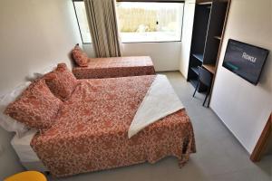 嘎林海斯港Condôminio Velas do Porto的一间卧室设有两张床、一台电视和一扇窗户。