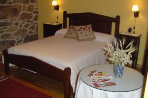 Rairiz de Veiga卡萨瑞克托拉康达旅馆的一间卧室配有一张床和一张桌子,桌子上配有四柱床。