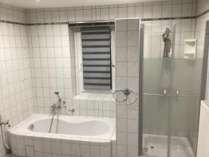 米特韦达Hotel Eintracht的一间带浴缸和淋浴的浴室,配有玻璃门