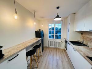 梅尔维尔弗朗瑟维尔普拉格Bel appartement plein centre 100m de la mer的厨房配有白色橱柜和带凳子的台面