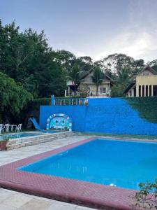 瓜拉米兰加Chalé Suíço的一个带蓝色墙壁的游泳池和一个游乐场