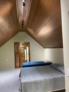 瓜拉米兰加Chalé Suíço的一间卧室设有一张带木制天花板的大床