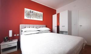 乌马格Apartment Violetta-Punta的卧室配有白色的床和红色的墙壁